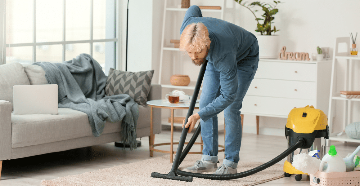 92108ec2-young-man-hoovering-carpet-home-1-1.png